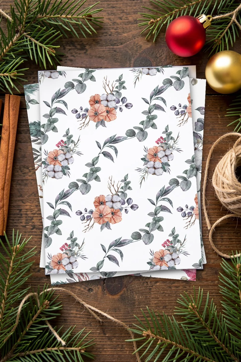 Watercolor paper with eucalyptus branches and peach flowers, with poinsettia and cotton sheets under it, on a dark wooden table with pine branches