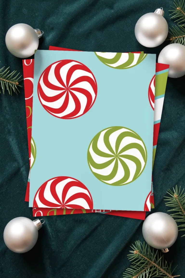 Peppermint candy Christmas scrapbook paper on light blue, printed sheets stacked, on dark teal velvet with silver baubles and fir twigs