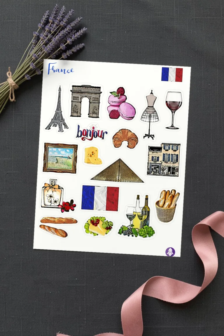 Printed sheet of Paris stickers with the Eiffel Tower, the Arc de Triomphe, macarons and a croissant, on charcoal grey linen with dried lavender and a dusty pink silk ribbon